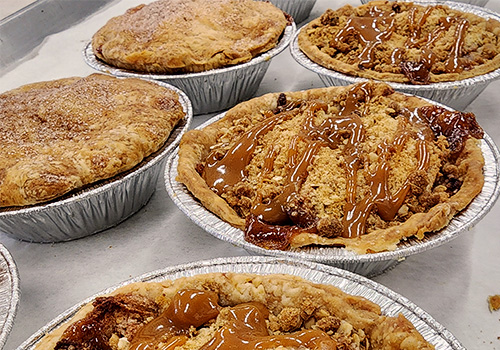 Several apple crumble pies with a caramel drizzle on top.
