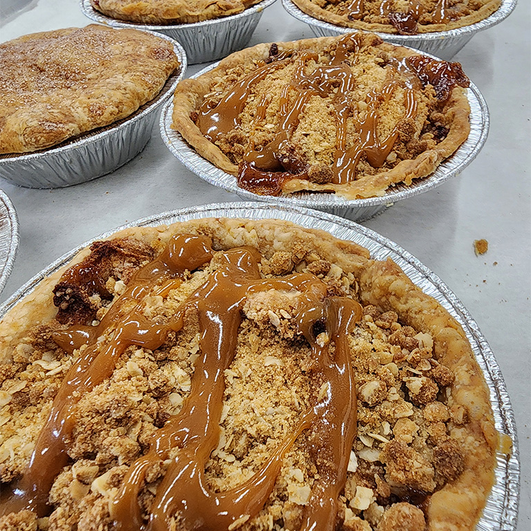 Decadent apple crumble pies with a caramel drizzle on top.
